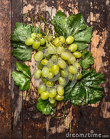 Fresh bright grapes on a branch with leaves on dark wooden background, top view Stock Photo