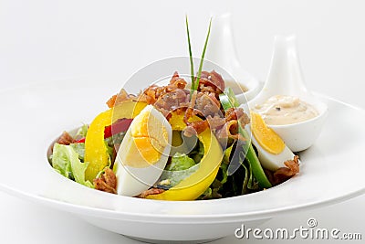 Fresh Caesar Salad with Deep-fried Bacon, Boiled Eggs & mayonnaise, Italian dressing on White Porcelain Round plate, on White Stock Photo
