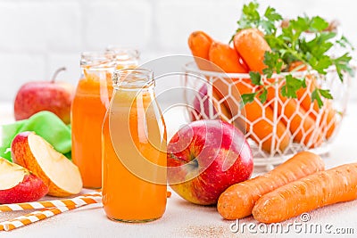 Fresh carrot and apple juice on white background. Carrot and apple juice in glass bottles on white table, closeup Stock Photo