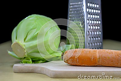 Fresh carrot grated on a metal kitchen grate. Vegetables prepared for salad with a meal on the kitchen table Stock Photo