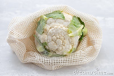 Fresh cauliflower with reusable bag on ceramic background Stock Photo