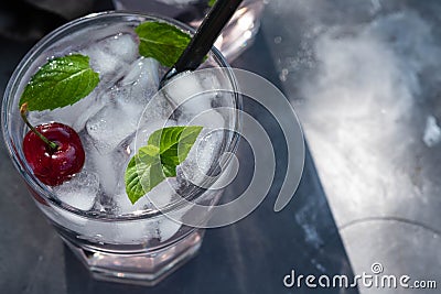 Fresh cherry cocktail. Fresh summer cocktail with cherry and ice cubes. Glass of cherry soda drink on dark stone Stock Photo