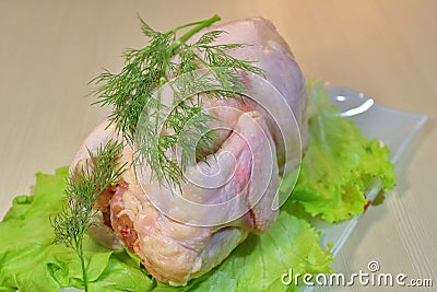 Fresh chicken with lettuce and herbs on a wooden board on the table. Stock Photo