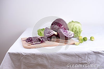 Fresh chopped red cabbage, early cabbage head, brussels sprouts on a cutting board with a knife on a white background Stock Photo
