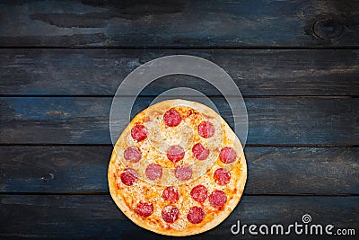 Fresh classic pepperoni pizzai on a dark wooden background. Top view bottom orientation Stock Photo