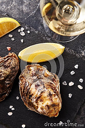 Fresh closed oysters with lemon on slate plate Stock Photo
