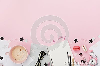 Fresh coffee, macaron, office supply, alarm clock and notebook on pink pastel table top view. Flat lay style. Cozy breakfast. Stock Photo