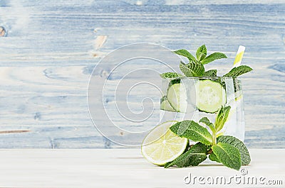 Fresh cool lemonade with mineral water, lime, cucumber, mint, ice on light blue wood plank. Stock Photo