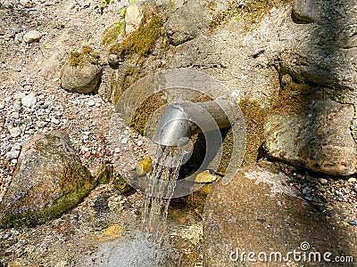 A fresh and cool spring flows from the ground. Cool and delicious spring water. Natural underground water source Stock Photo