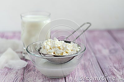 Fresh cottage cheese in a transparent bowl with raisins. In the background is a glass of kefir. Fermented foods. Good bacteria for Stock Photo