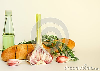 Fresh crispy baguette with garlic oil and herbs. A delicious still life of baguette, young garlic, fresh dill and a glass bottle Stock Photo