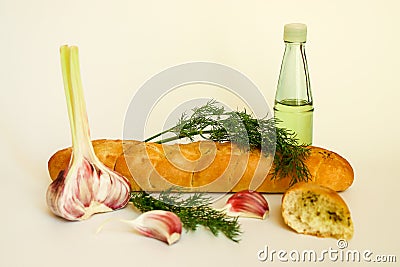 Fresh crispy baguette with garlic oil and herbs. A delicious still life of baguette, young garlic, fresh dill and a glass Stock Photo