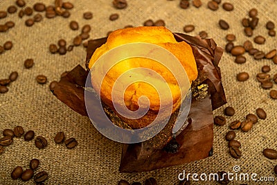 Fresh cupcake and coffee beans on a homespun fabric with a rough texture. Close up Stock Photo