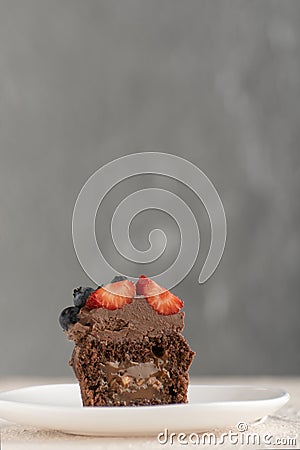 Fresh cupcake decorated with chocolate cream and berries on glass plate. Chocolate muffins with butter glaze Stock Photo