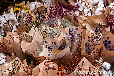Fresh cut bunches of purple, orange, yellow, green, pink flowers wrapped for sale Stock Photo