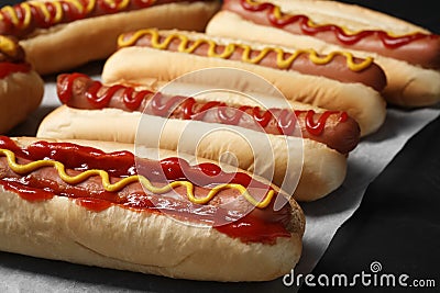 Fresh delicious hot dogs with sauces on black table, closeup Stock Photo