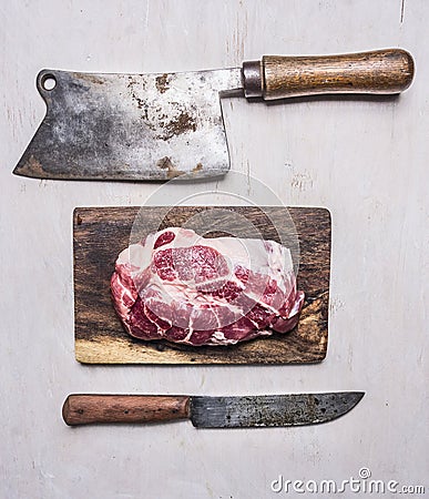 Fresh, delicious raw pork steak on a cutting board with a meat cleaver and a knife wooden rustic background top view close up Stock Photo