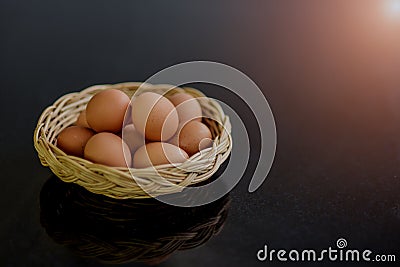 Fresh eggs in many wicker baskets on a black stone table prepared as a raw material for cooking. Stock Photo