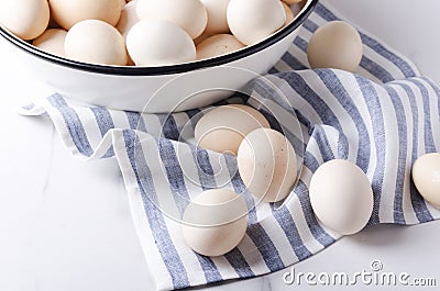 Uncooked eggs just collected on the farm.Lot of eggs in the boel and on the napkin.Kitchen table and eggs on it Stock Photo