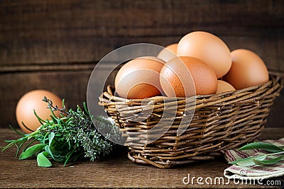 Fresh eggs in a willow basket with aromatic herbs Stock Photo