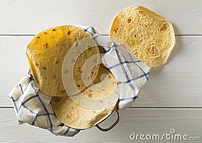 Fresh, empty wheat tortilla flat lay top view on dishcloth on white wooden table Stock Photo