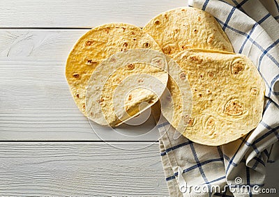 Fresh, empty wheat tortilla flat lay top view on dishcloth on white wooden table Stock Photo