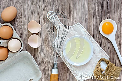 Fresh farm eggs on a wooden rustic background. Separated egg white and yolks, broken egg shells. Stock Photo