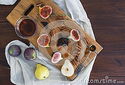 Fresh figs, pears and pekan nuts with honey on a wooden board Stock Photo