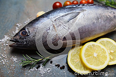 Fresh fish with herbs spices rosemary tomato and lemon - Raw fish seafood on black plate background , Longtail tuna , Eastern Stock Photo