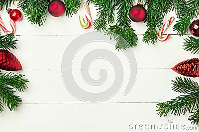 Fresh fluffy fir tree branches red ornament balls candy canes on white plank wood backdrop. Styled Christmas New Year background Stock Photo