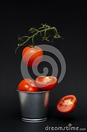 fresh flying tomatoes on a branch in the air. tomatoes in a tin bucket. healthy diet. Stock Photo