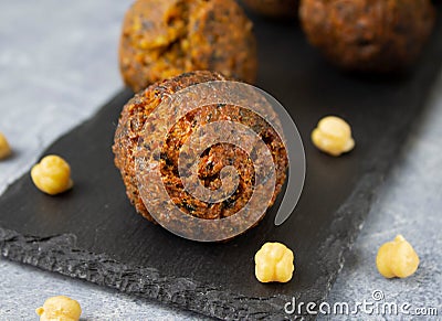Fresh fried falafel on black slate board and chickpea beans on cement gray surface Stock Photo