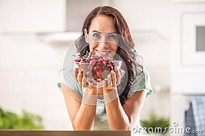 Fresh fruit harvest in the form of cherries in a seethrough bowl held by a woman indoors Stock Photo