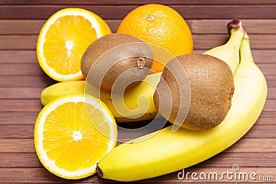 Fresh fruits banana, kiwi, orange isolated on wooden background. Stock Photo