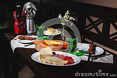 fresh Georgian meal with khachapuri, shashlik kebab with beef or lamb meat, tomato with cheese and green tarragon drink Stock Photo