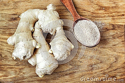 Fresh ginger root and ginger powder in the spoon on wooden background, raw material for cooking Stock Photo