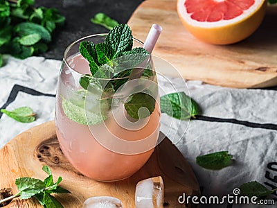 Fresh grapefruit and mint homemade lemonade with ice in glass on wood board. Summer drink with citrus and herbs Stock Photo