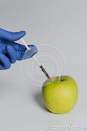 Apple injected with pesticides needle syringe Stock Photo