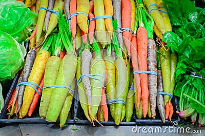 Fresh green cabbage, rainbow carrots and spinach in rubber bands at food store in America Stock Photo