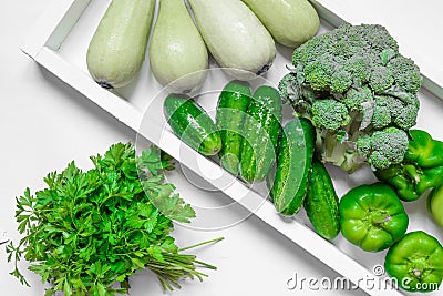 Fresh green vegetables - courgette, cucumber, paprika, parsley, broccoli on white tray and white background. Healthy snacks, Stock Photo