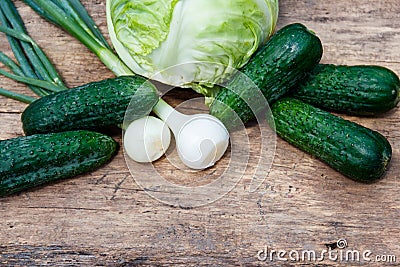 Fresh green vegetables on rustic wooden table. Cabbage, cucumbers and onion on wood table. Top view Stock Photo