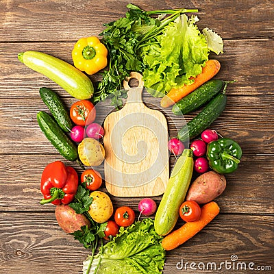Fresh green vegetables zucchini cucumber greens pepper cutting board on wooden background. Healthy food vegetarianism. Stock Photo