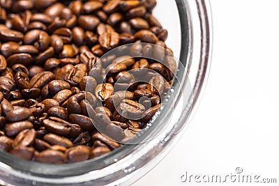 Fresh and ground roasted coffee beans from the coffee plant inside a cylindrical glass jar Stock Photo