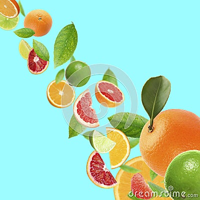 Fresh juicy citrus fruits and green leaves falling on cyan background Stock Photo