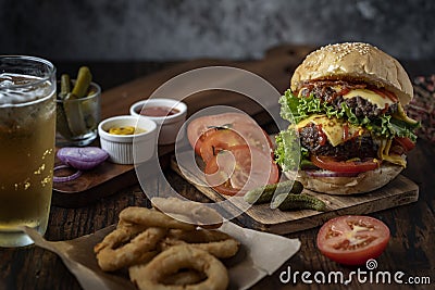 Fresh and juicy hamburger. Cheese burger with beef or bacon, patty tomato, onion ring and sparkling water or beer. Junk food to Stock Photo