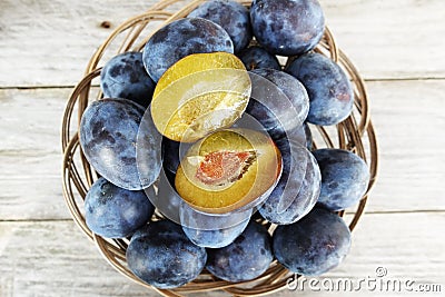 Fresh juicy plums in wooden basket, healthy autumn fruits Stock Photo