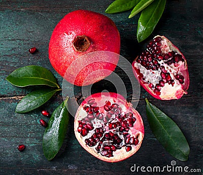 Fresh juicy pomegranate - whole and cut, with leaves on a wooden vintage background, top view, horizontal Stock Photo