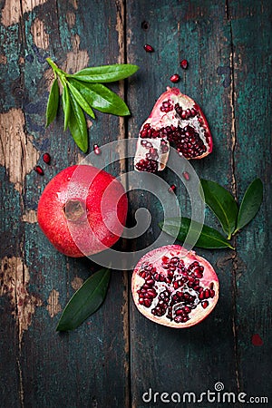 Fresh juicy pomegranate - whole and cut, with leaves on a wooden vintage background, top view, horizontal Stock Photo