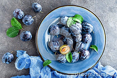 Fresh juicy sweet plums on plate with leaves Stock Photo