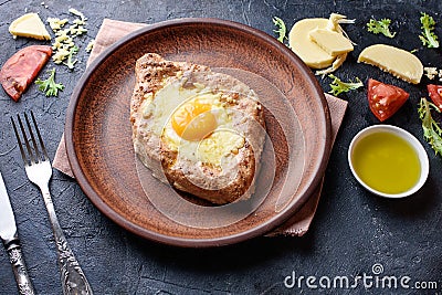 Fresh khachapuri with wholegrain flour, cottage cheese, egg, sulugini cheese, vegetables, butter, greens, plate, fork knife Stock Photo